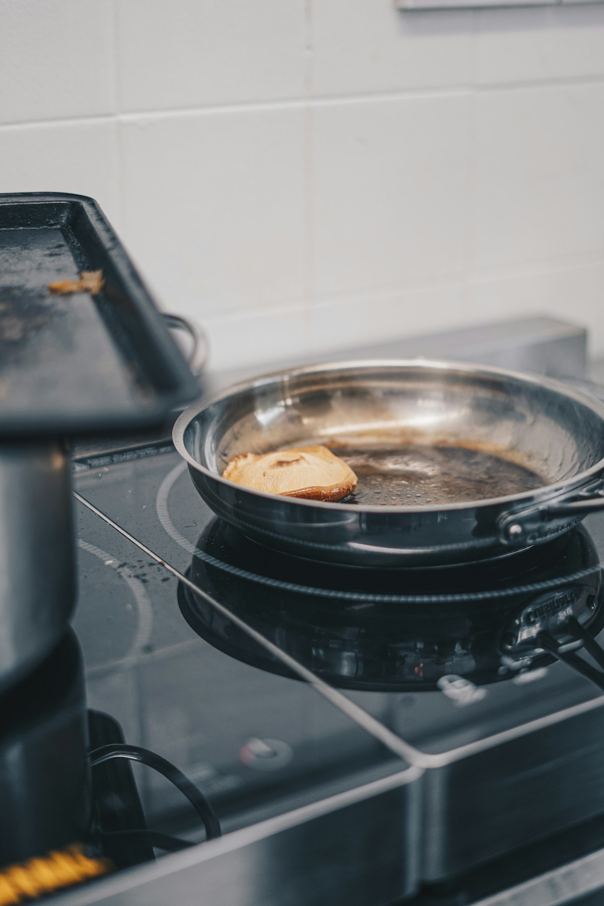 Een roestvrijstalen koekenpan in gebruik op een glazen kookplaat